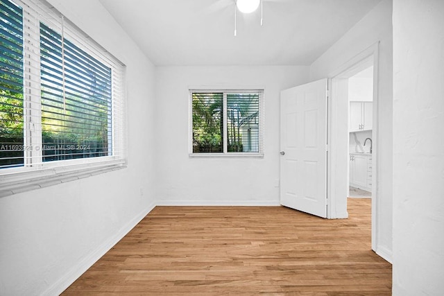 spare room with a wealth of natural light, sink, ceiling fan, and light wood-type flooring