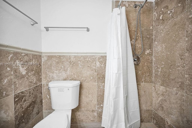 bathroom featuring a shower with curtain, toilet, and tile walls