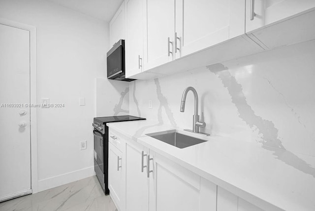 kitchen featuring decorative backsplash, white cabinetry, sink, and black / electric stove