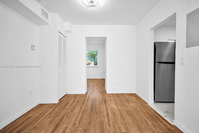 interior space with stainless steel refrigerator, electric panel, and light hardwood / wood-style floors