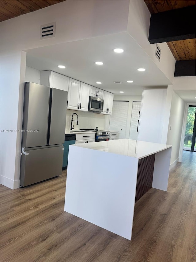 kitchen with stainless steel appliances, dark wood-type flooring, wooden ceiling, a center island, and white cabinetry