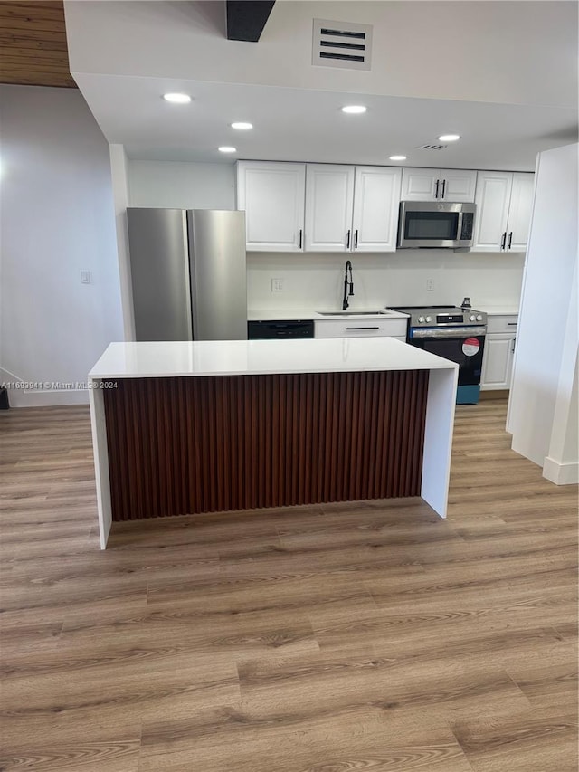 kitchen featuring a center island, sink, appliances with stainless steel finishes, light hardwood / wood-style floors, and white cabinetry