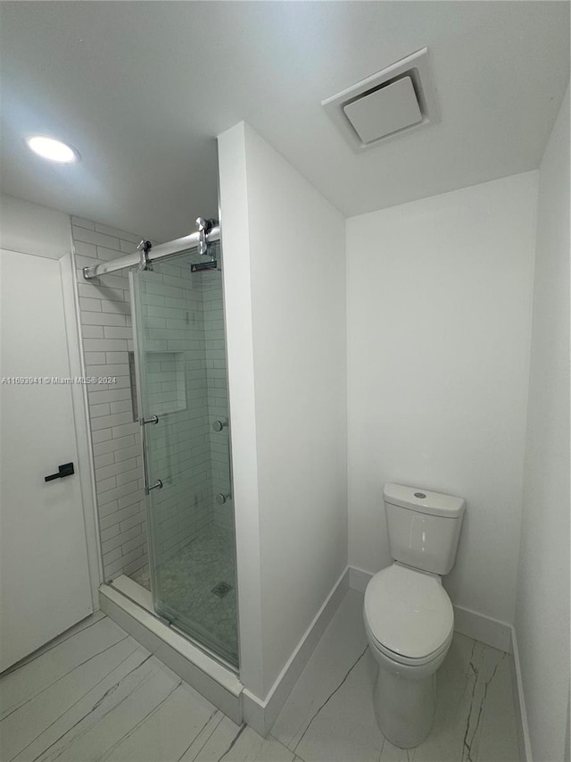 bathroom with toilet and a shower with shower door