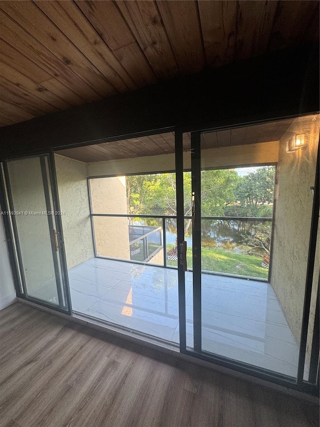 doorway with hardwood / wood-style flooring, beam ceiling, a water view, and wood ceiling