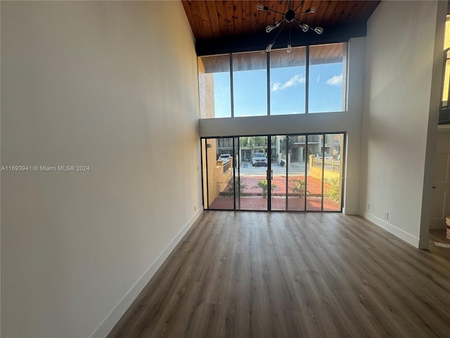 unfurnished living room with beam ceiling, hardwood / wood-style floors, wood ceiling, and a high ceiling