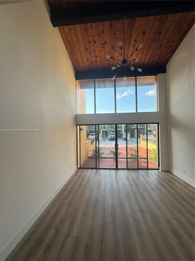 spare room with wood-type flooring, a towering ceiling, wooden ceiling, and beam ceiling