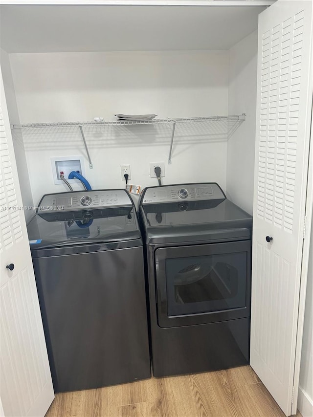 clothes washing area with light hardwood / wood-style floors and washing machine and dryer