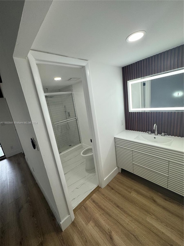 bathroom featuring hardwood / wood-style floors, vanity, an enclosed shower, and toilet