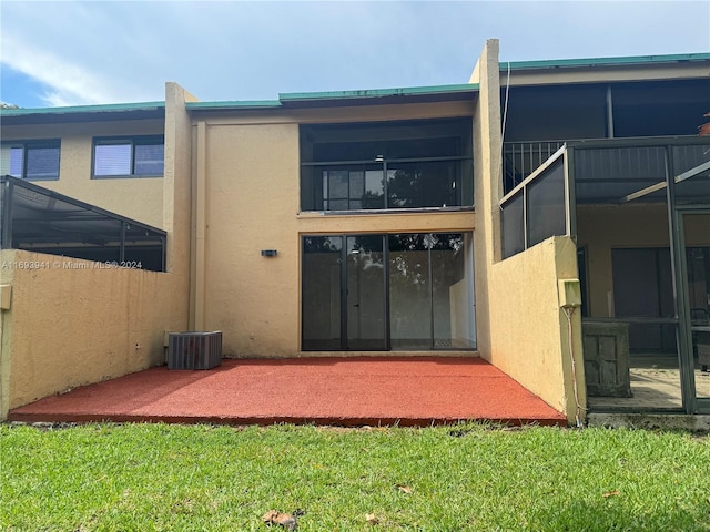 rear view of property featuring a lawn and central AC unit