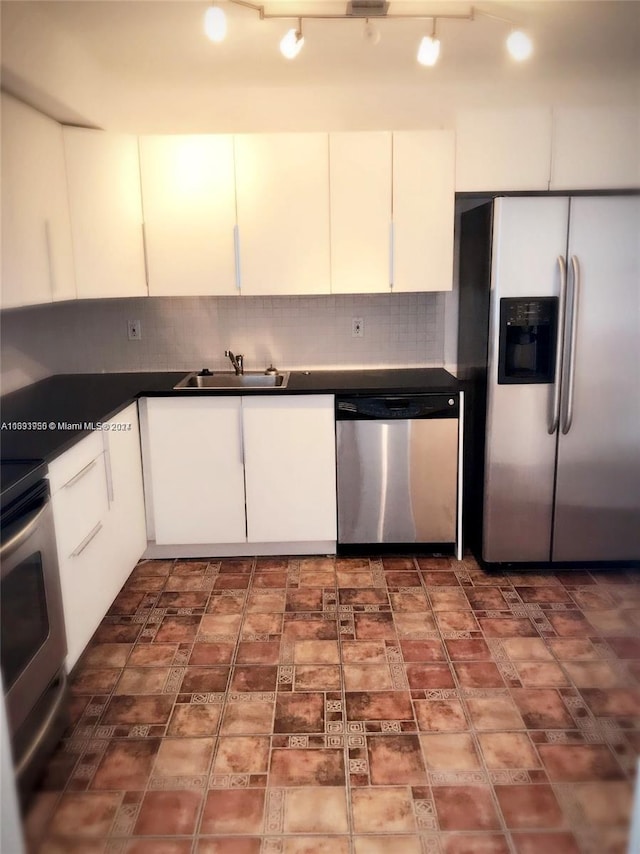 kitchen featuring backsplash, track lighting, white cabinets, sink, and stainless steel appliances