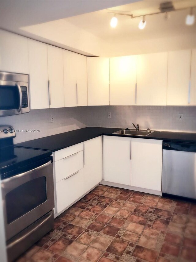 801 Three Islands Blvd Unit 411, Hallandale Beach, FL 33009 - kitchen featuring appliances with stainless steel finishes, a sink, tasteful backsplash, dark countertops, and white cabinetry