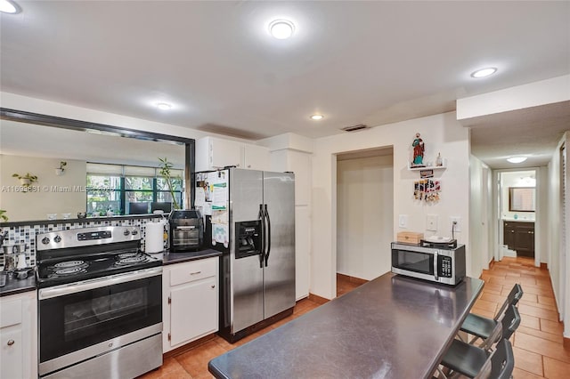 kitchen with stainless steel appliances, white cabinetry, and backsplash