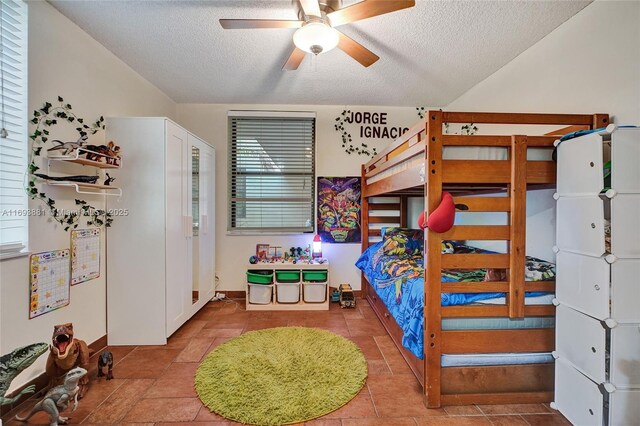 tiled bedroom with ceiling fan and a textured ceiling