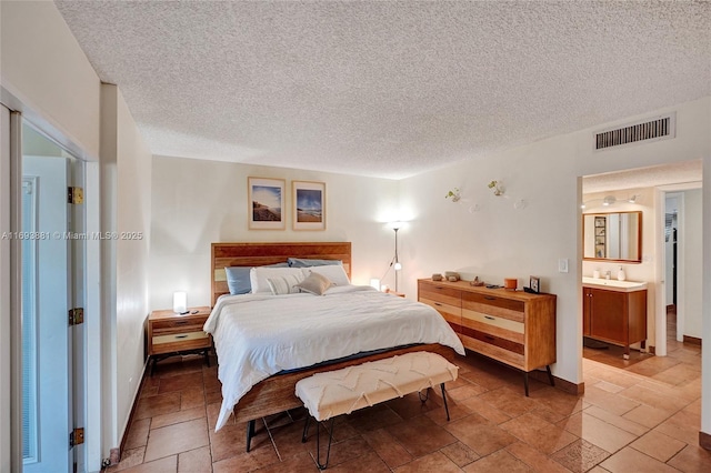 bedroom featuring connected bathroom and a textured ceiling