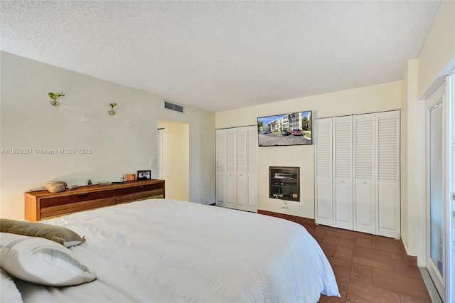 bedroom with two closets and a textured ceiling