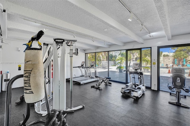 gym with rail lighting and a textured ceiling