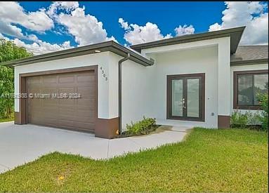 view of front of home featuring a front lawn, a garage, and french doors