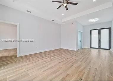 empty room with ceiling fan, light hardwood / wood-style floors, and french doors