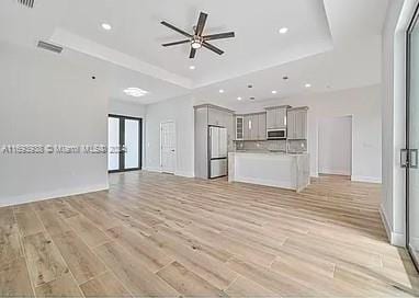 unfurnished living room with ceiling fan, light wood-type flooring, and french doors