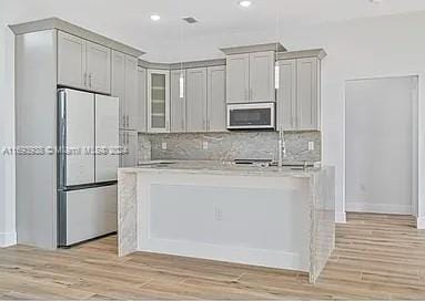 kitchen featuring backsplash, gray cabinets, white fridge, and light hardwood / wood-style floors