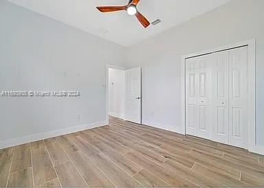 unfurnished bedroom with a closet, light hardwood / wood-style flooring, and ceiling fan