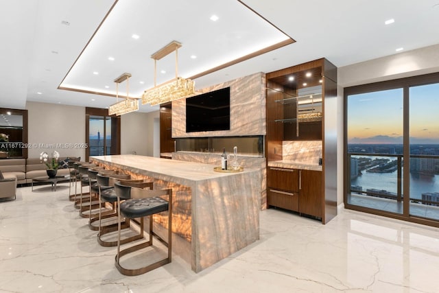 kitchen featuring pendant lighting, a kitchen bar, a tray ceiling, and decorative backsplash