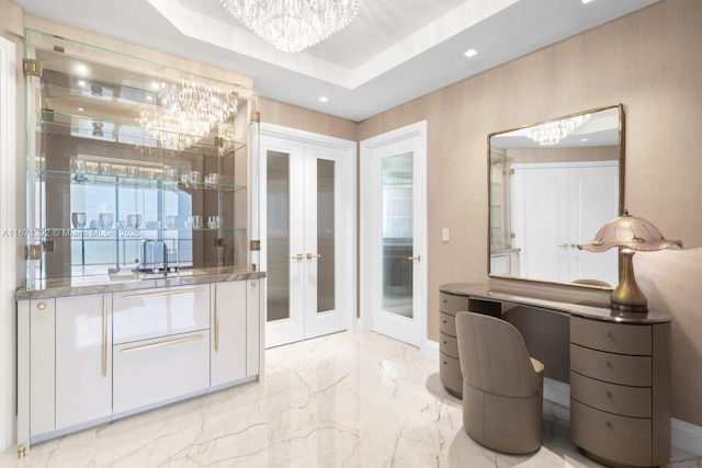 interior space with french doors, a tray ceiling, sink, and a notable chandelier