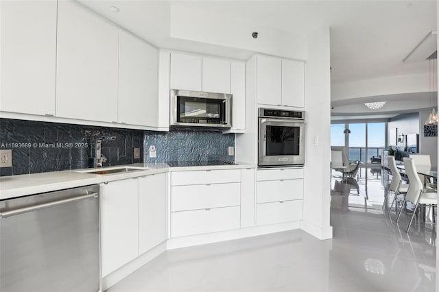 kitchen with a water view, sink, light tile patterned floors, white cabinetry, and stainless steel appliances