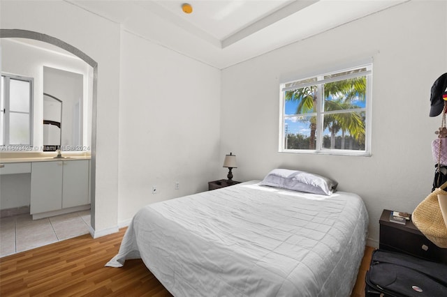 bedroom featuring ensuite bath, sink, and light wood-type flooring