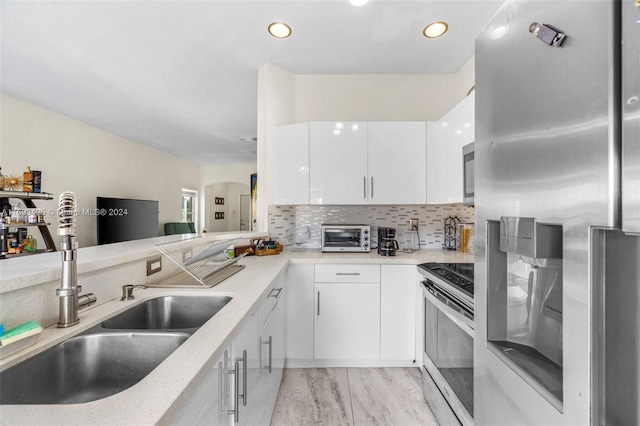 kitchen featuring white cabinets, sink, appliances with stainless steel finishes, and tasteful backsplash