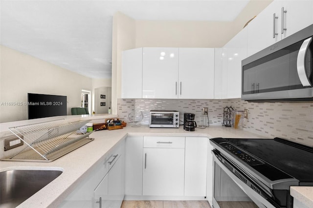 kitchen with white cabinets, backsplash, and appliances with stainless steel finishes