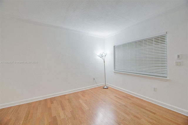 spare room with light wood-type flooring and ornamental molding