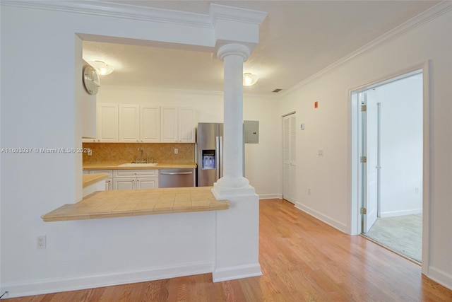 kitchen with appliances with stainless steel finishes, backsplash, crown molding, sink, and white cabinetry