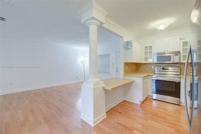 kitchen with white cabinets, ornate columns, stainless steel appliances, and tasteful backsplash