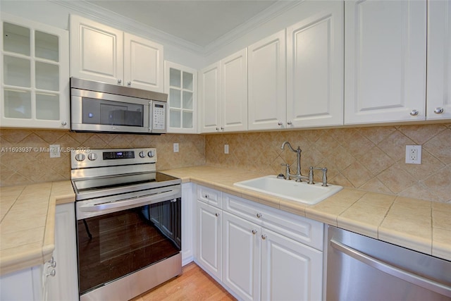 kitchen with appliances with stainless steel finishes, tasteful backsplash, white cabinetry, and sink