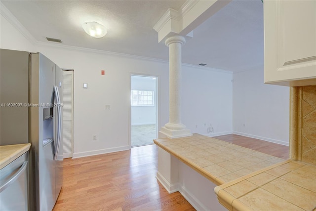 kitchen with stainless steel refrigerator with ice dispenser, decorative columns, crown molding, tile countertops, and light hardwood / wood-style flooring