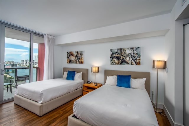 bedroom with access to exterior, dark hardwood / wood-style flooring, and a wall of windows