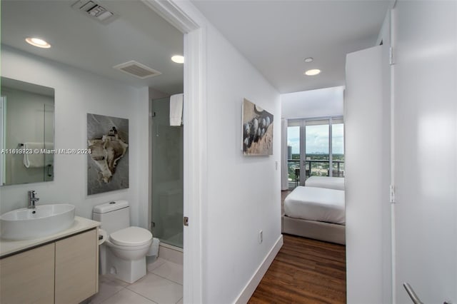 bathroom with hardwood / wood-style floors, vanity, an enclosed shower, and toilet