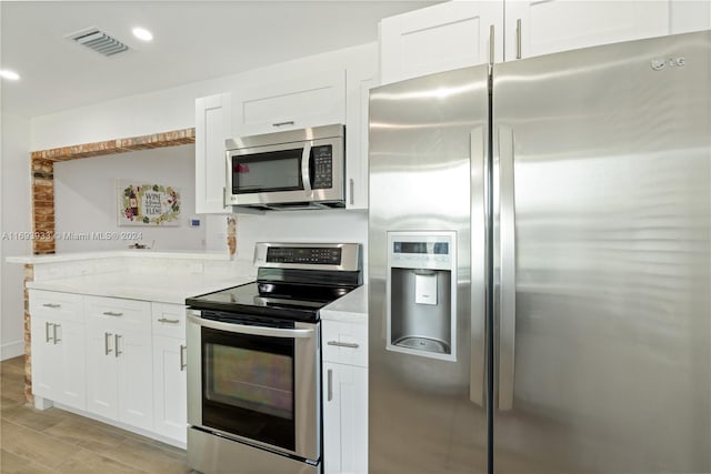 kitchen featuring white cabinetry, light stone countertops, light wood-type flooring, and appliances with stainless steel finishes