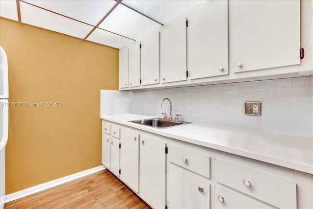 kitchen featuring sink, a drop ceiling, light hardwood / wood-style flooring, decorative backsplash, and white cabinets