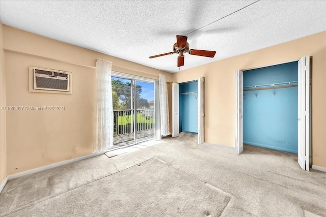 unfurnished bedroom featuring a textured ceiling, ceiling fan, light colored carpet, and two closets