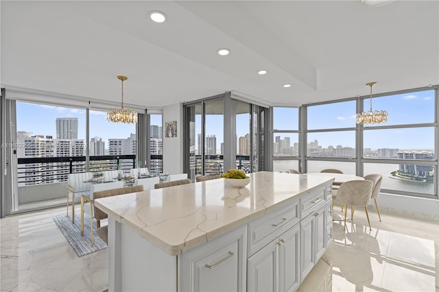 kitchen with white cabinetry, light stone countertops, a center island, and hanging light fixtures