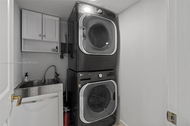 clothes washing area featuring cabinets, stacked washing maching and dryer, and sink