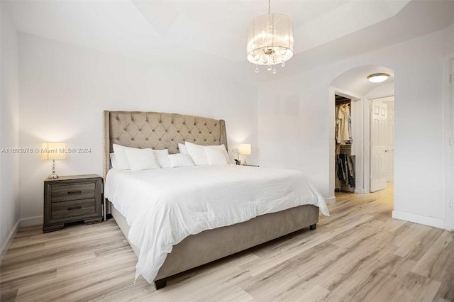 bedroom featuring an inviting chandelier, a spacious closet, a closet, and light hardwood / wood-style flooring