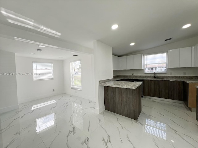 kitchen with light stone countertops, sink, white cabinets, and dark brown cabinets