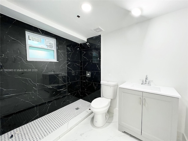 bathroom featuring vanity, toilet, and a tile shower