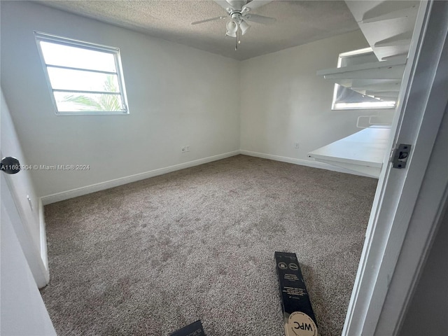 carpeted empty room with ceiling fan and a textured ceiling