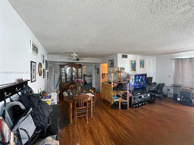 living room with a textured ceiling, dark hardwood / wood-style flooring, and ceiling fan