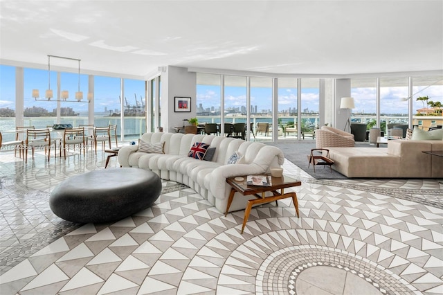 living room with an inviting chandelier, a water view, a healthy amount of sunlight, and a wall of windows