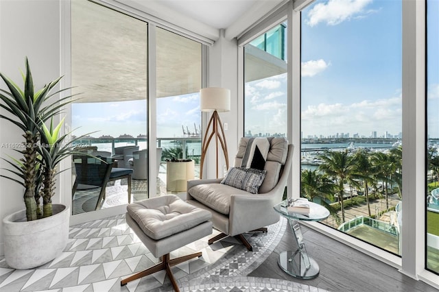 sitting room featuring hardwood / wood-style flooring, floor to ceiling windows, and a water view